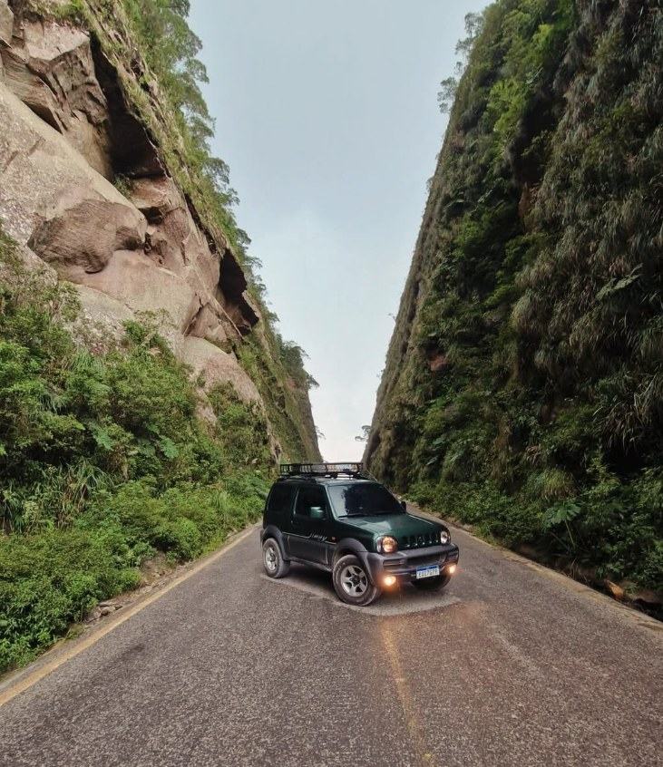 Jimny na estrada entre paredões de pedra.